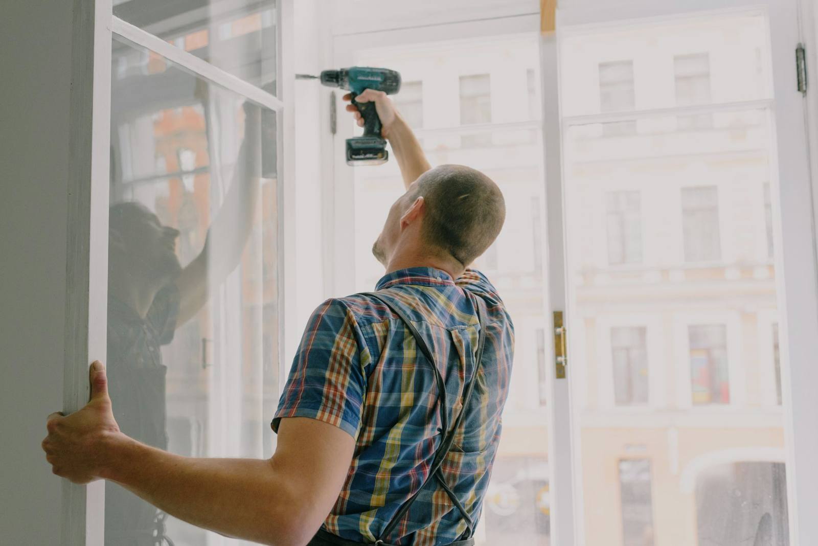 Fitter drilling a new window frame into place